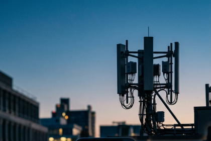 Smartphone con Network Signal Guru che mostra le metriche 5G NSA davanti a una BTS