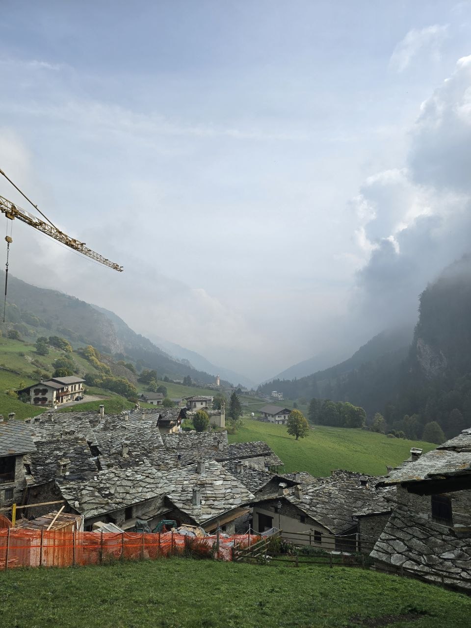 Borgata in pietra della Valle Varaita di Bellino con i tetti in lose e la valle che sale verso Sant'Anna tra le nuvole